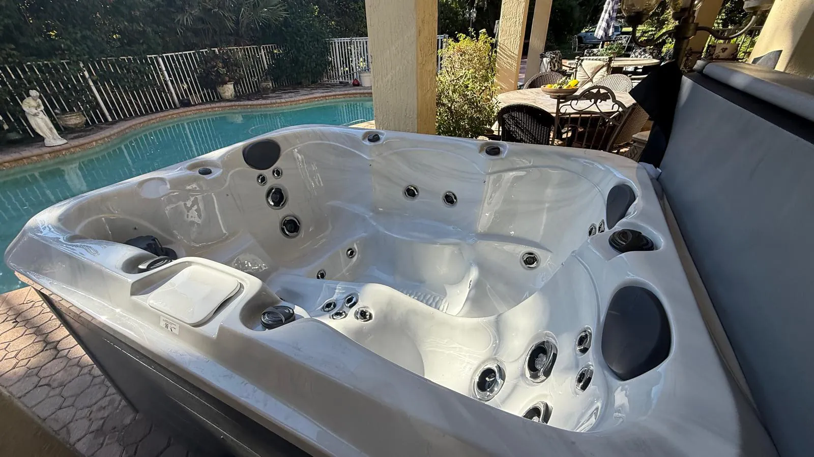 Maple M320 hot tub on a covered patio next to a pool in Avenir