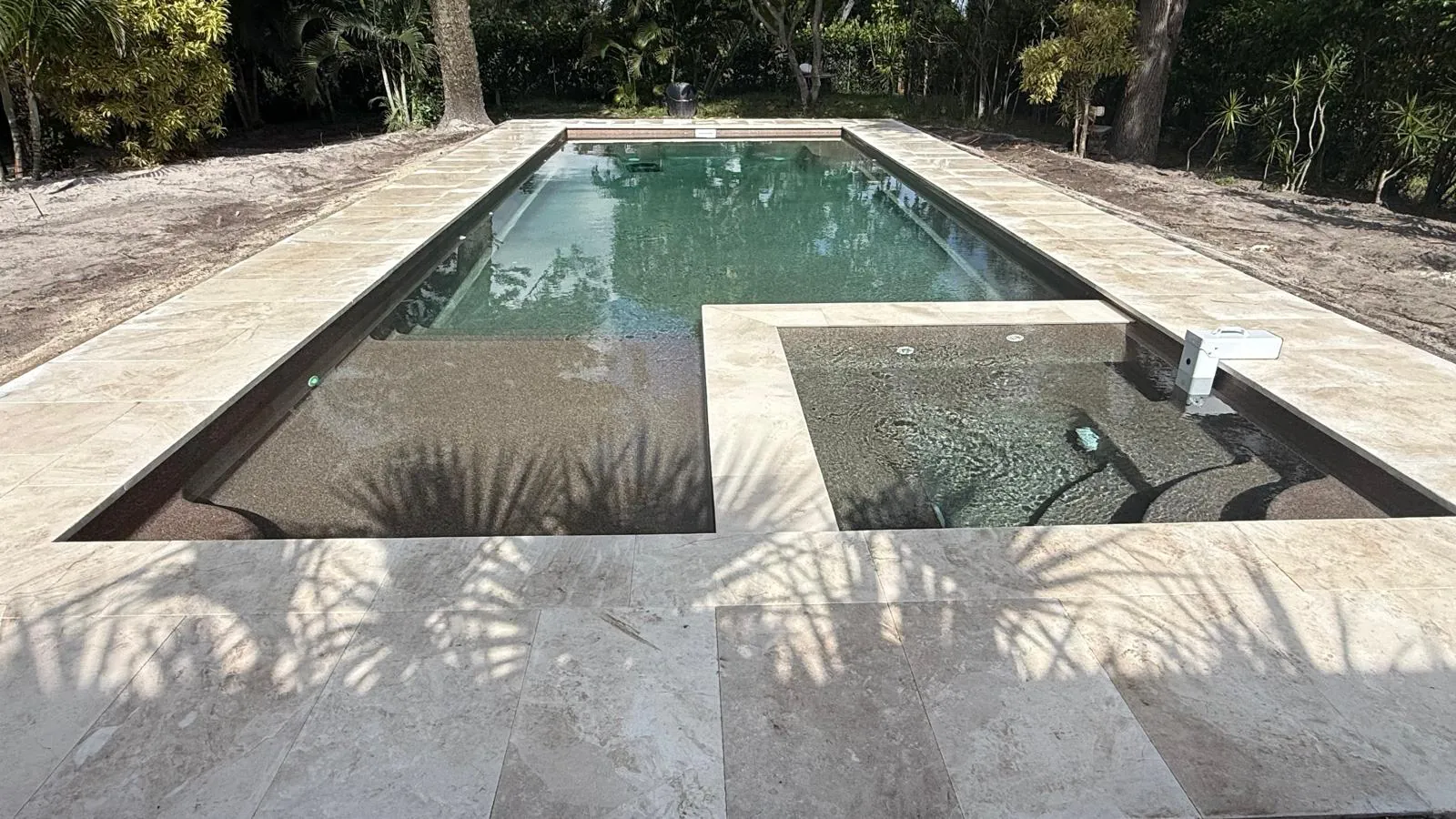 Light stone deck around the pool and built-in spa