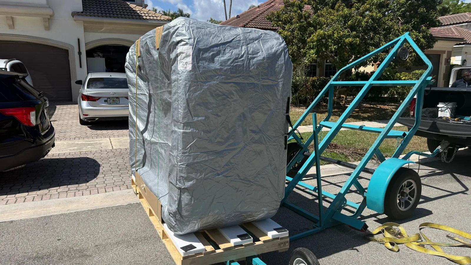 Wrapped hot tub on its side on a dolly in the driveway