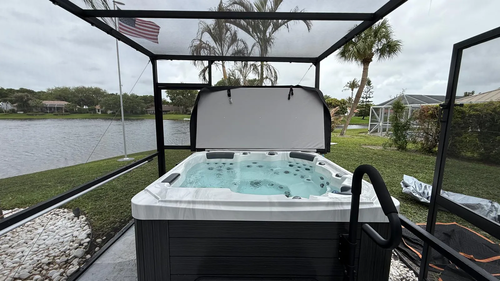Be Well U916 hot tub inside a screen enclosure beside a lake in Jupiter