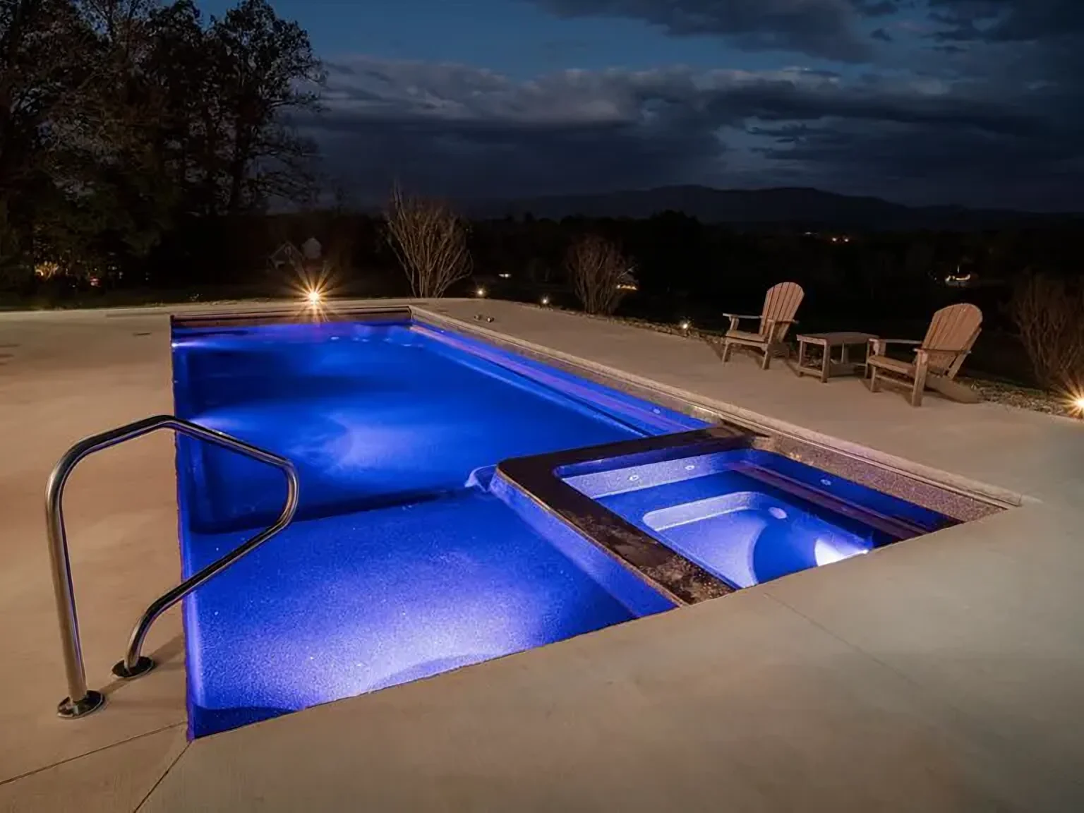 Latham Astoria 14 fiberglass pool with built-in spa, lit at night