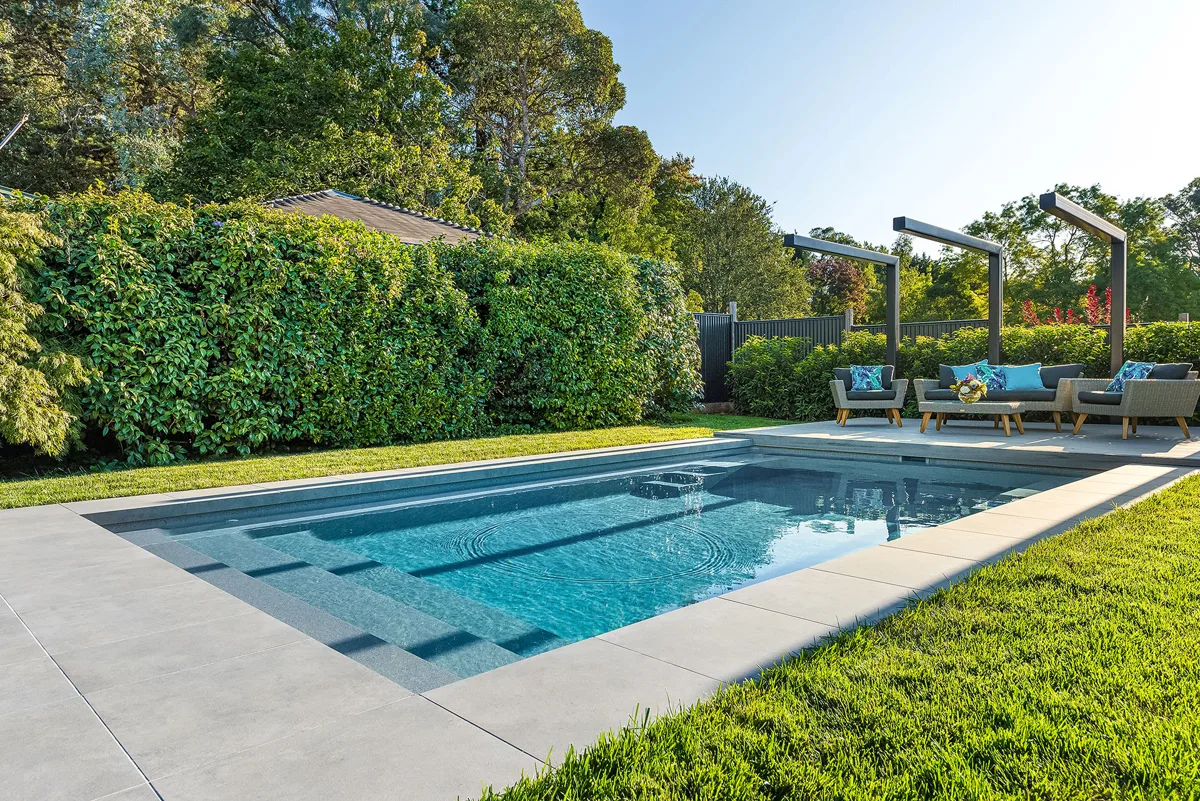 Latham Athens 13.23 rectangular fiberglass pool beside a wood deck and lawn
