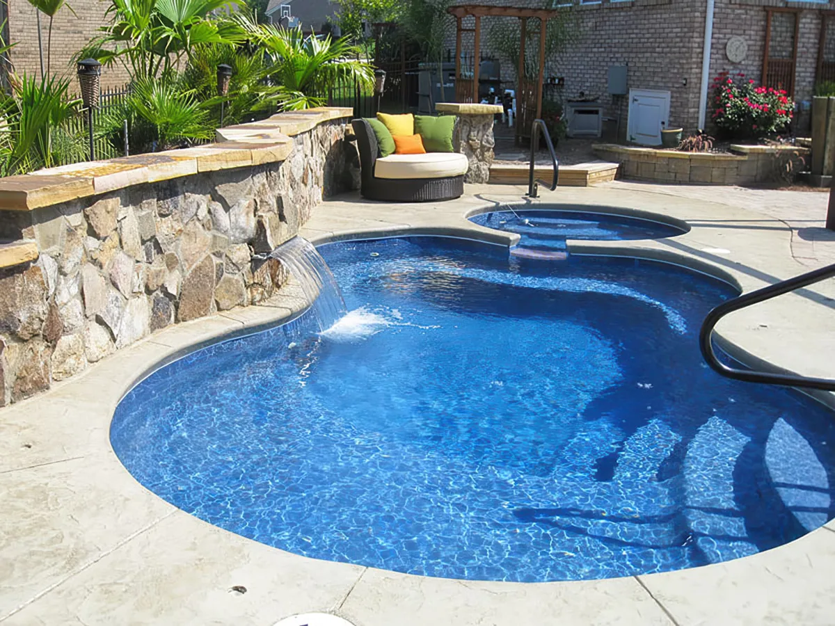 Latham Axiom 14 Deluxe fiberglass pool with a raised spa spilling into the pool