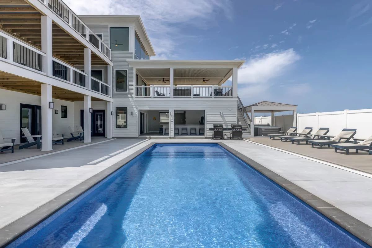 Latham Corinthian 14 fiberglass pool behind a coastal home with loungers