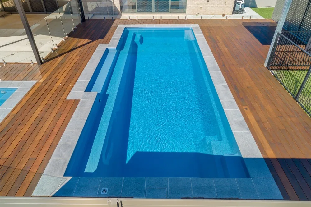 Built-in bench along a Latham Tuscan 14.30 fiberglass pool on a wood deck