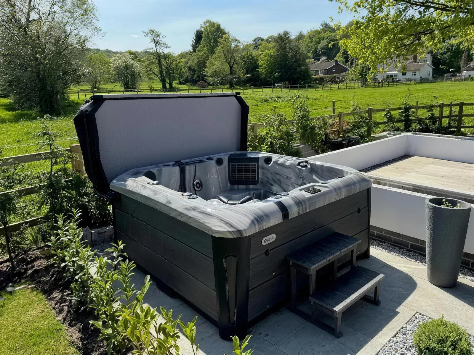 Platinum Spas Tokyo hot tub with its cover lifted on a sunny garden patio