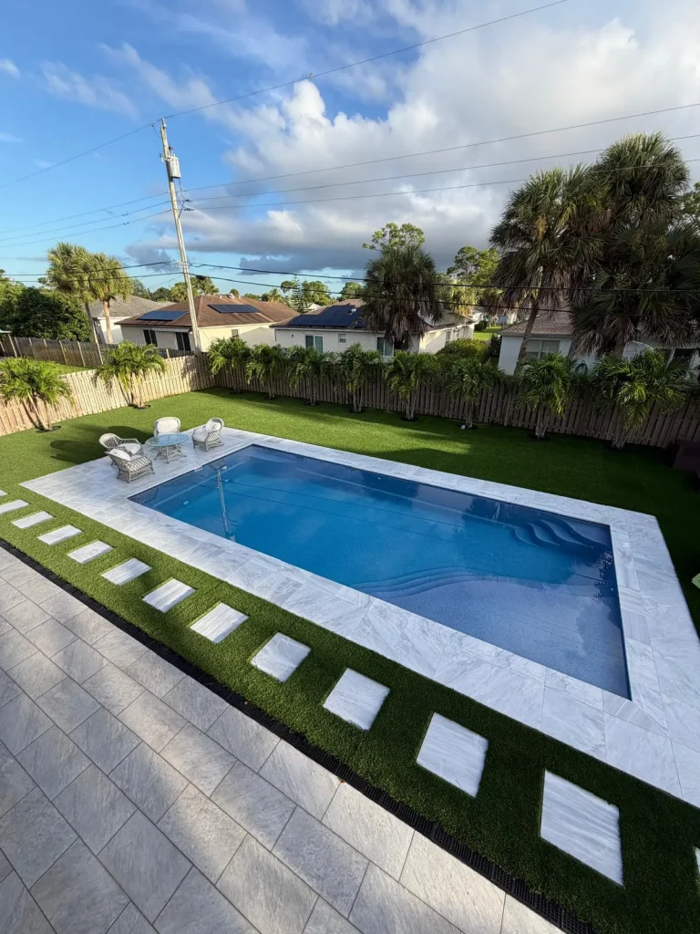 Finished fiberglass pool with a paver deck, turf and stepping pavers