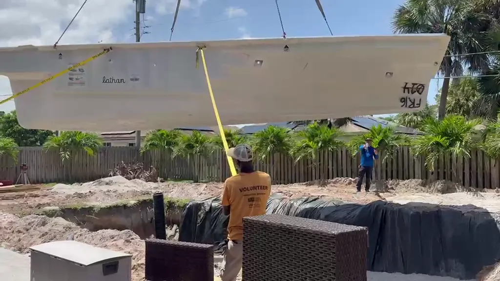 Fiberglass pool shell being lowered by crane