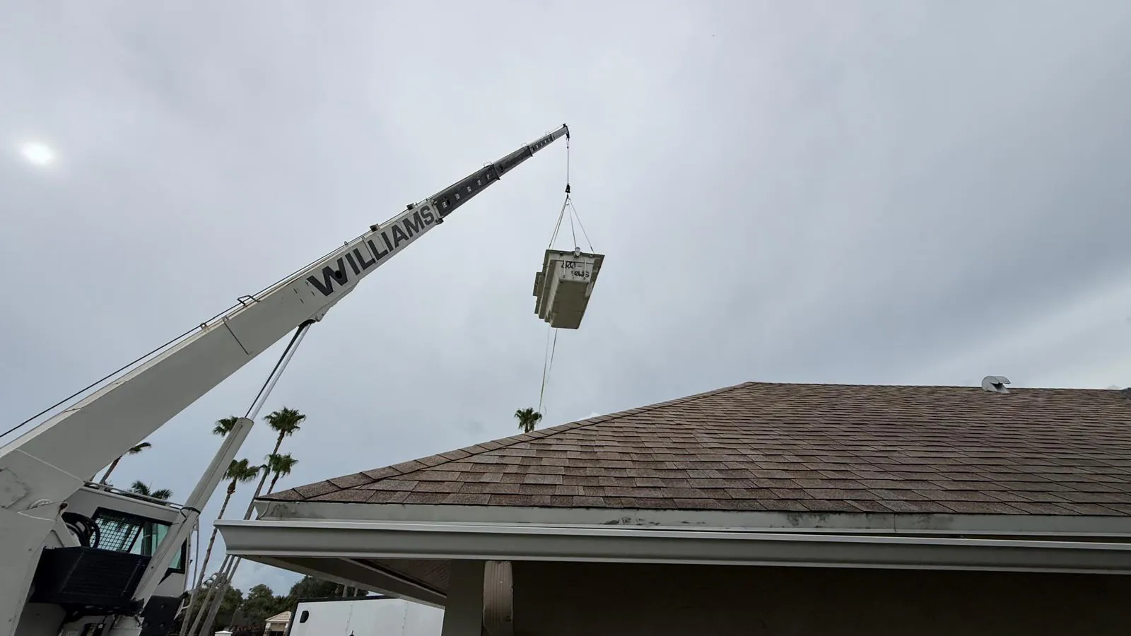 Crane carrying the pool shell over the roof
