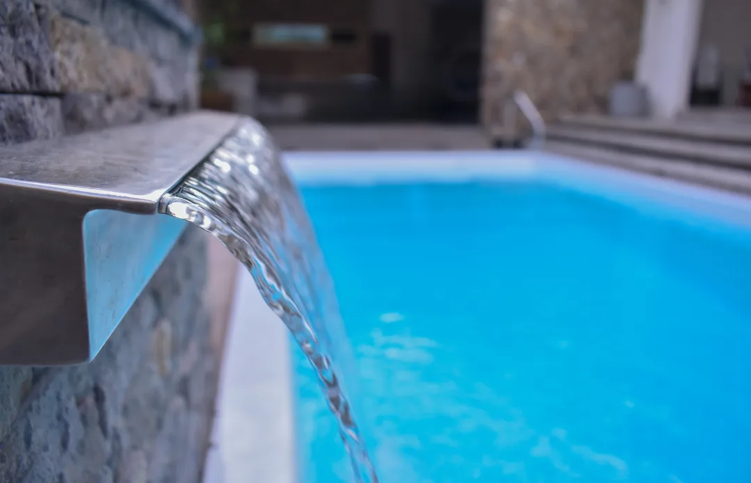 Water feature pouring into an X-Pools Key West fiberglass pool