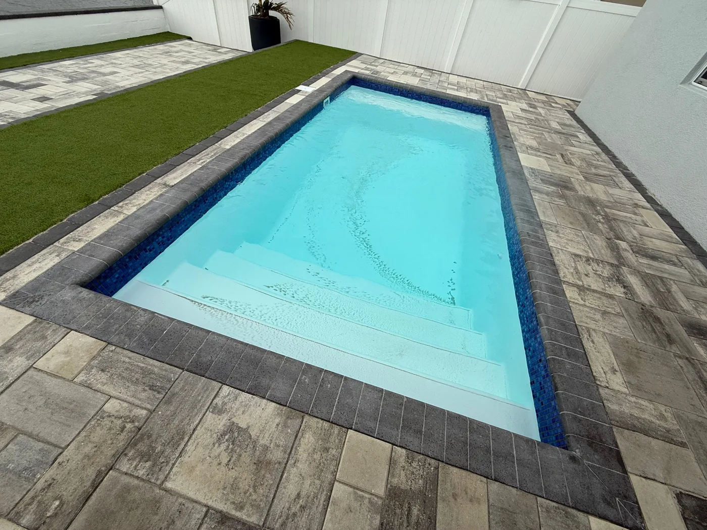 X-Pools Miami fiberglass pool set in gray pavers